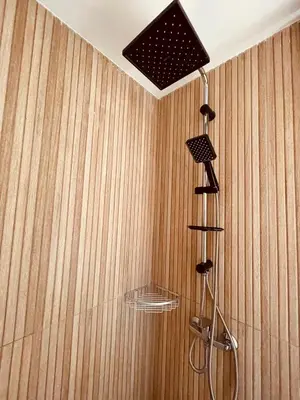 a shower in a room with a wooden wall at Relax Family 01 - Cozy Entire Apartement in City Center in Ouarzazate