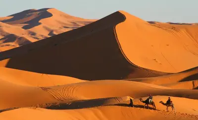 a group of people riding horses in the desert at Morocco Tour Itineraries in Merzouga