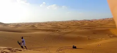 a man standing in the desert with a surfboard at Auberge merzouka in Rissani