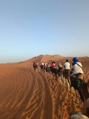 a group of people riding horses in the desert at Auberge merzouka in Rissani