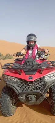 a person riding a red atv in the desert at Auberge merzouka in Rissani
