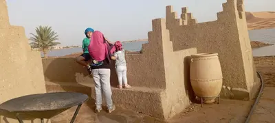 a man and a woman standing on a wall in the desert at Auberge merzouka in Rissani
