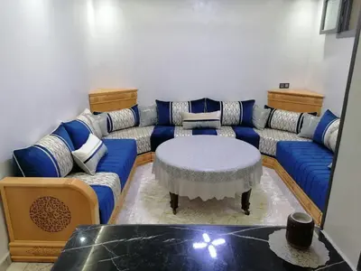 a living room with a blue couch and a table at Elbatoir in Oulad Akkou