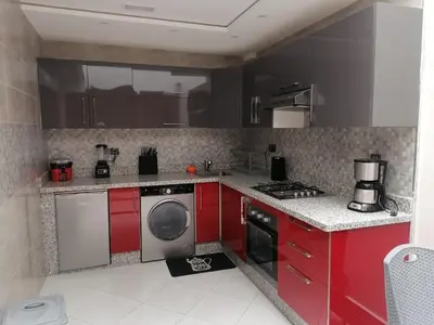 a kitchen with red cabinets and a washing machine at Elbatoir in Oulad Akkou