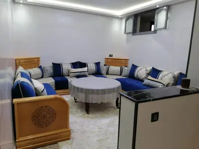 a living room with a blue couch and a table at Elbatoir in Oulad Akkou