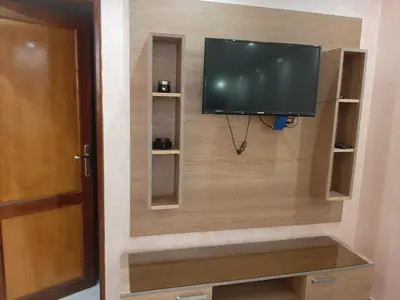 a flat screen tv on a wall with shelves at Chokri lamia in Ouled Khellouf