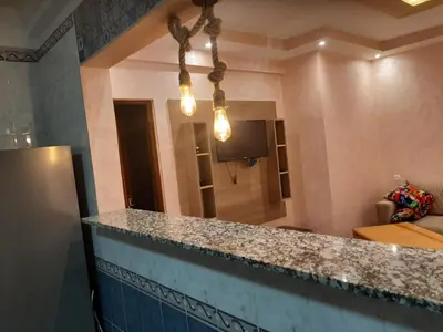 a kitchen with a counter top and a living room at Chokri lamia in Ouled Khellouf