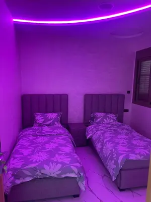 a purple bedroom with two beds and a pink light at AMB appartements in Oulad Akkou