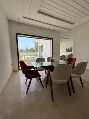a dining room with a glass table and chairs at villa prestigieuse avec piscine in Oulad Akkou