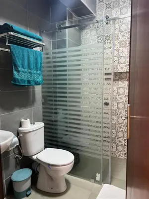 a bathroom with a toilet and a glass shower at Appartement Marrakech in Oulad Akkou