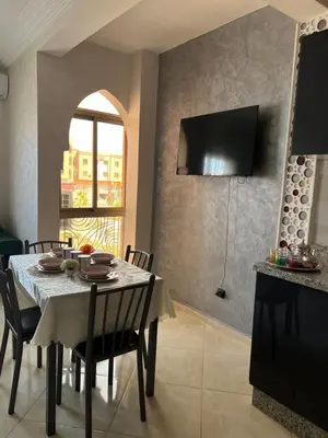 a dining room with a table with chairs and a television at Appartement Marrakech in Oulad Akkou
