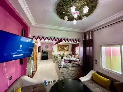 a living room with a pink wall and a tv at Le meilleur appartement à côté du grand stade sportif de Fès in Fès