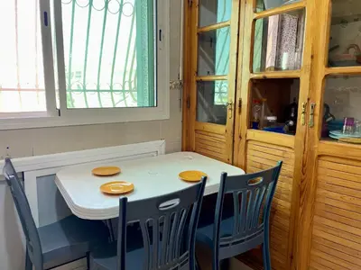 a dining room table with two chairs and a white table and a window at Le meilleur appartement à côté du grand stade sportif de Fès in Fès
