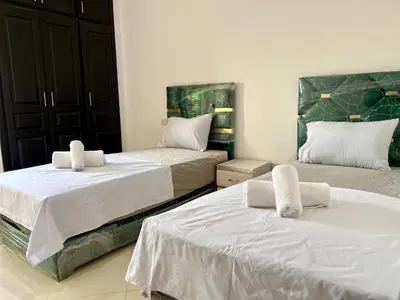 a bedroom with two beds with white sheets at Residence Nasr Fes - Family & Traveler Apartments in Fès
