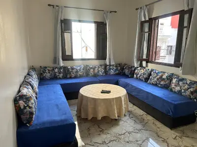 a living room with a blue couch and a table at Appartement Martil in Oulad Akkou
