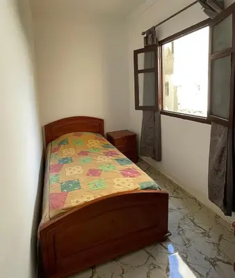 a bedroom with a bed with a comforter and a window at Appartement Martil in Oulad Akkou