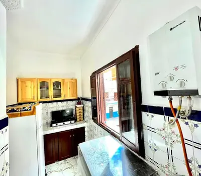 a kitchen with a white refrigerator and wooden cabinets at Appartement Martil in Oulad Akkou