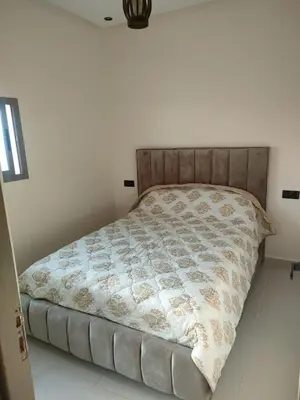a bed in a white room with a comforter at Dar essaouira in Oulad Akkou