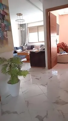 a living room with a potted plant on the floor at إقامة ياسمينه in Oulad Akkou