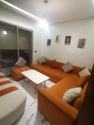 a living room with orange couches and a table at إقامة ياسمينه in Oulad Akkou