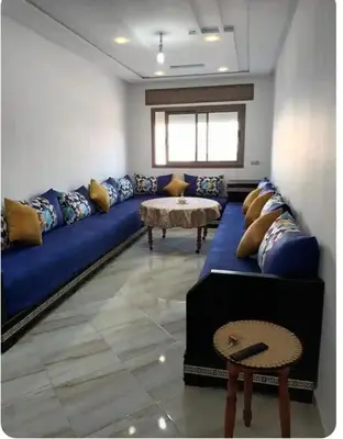 a living room with a blue couch and a table at Appartement martil in Oulad Akkou