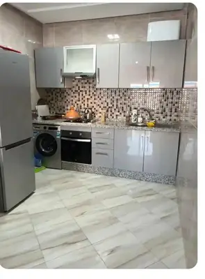a kitchen with white appliances and a tile floor at Appartement martil in Oulad Akkou