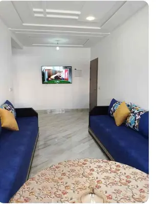 a living room with two blue couches and a tv at Appartement martil in Oulad Akkou