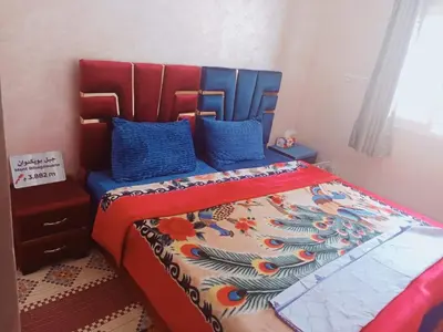 a bedroom with a bed with a red headboard and blue pillows at Gîte Ayour Atlas Tachddirt in Tacheddirt