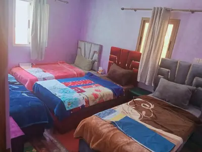 three beds in a room with purple walls at Gîte Ayour Atlas Tachddirt in Tacheddirt