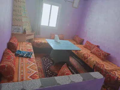 a room with a table and a couch with pillows at Gîte Ayour Atlas Tachddirt in Tacheddirt