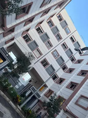 a tall white building with trees in front of it at عمارة المودة 2 in Oulad Akkou
