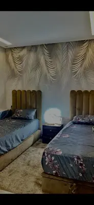 a bedroom with two beds with a tufted headboard at عمارة المودة 2 in Oulad Akkou