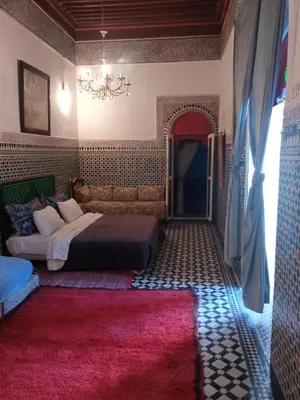 a bedroom with a bed and a pink rug at Suite in a 19 century palace in the heart of Medina in Fès