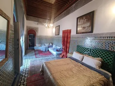 a bedroom with a bed and a couch in a room at Suite in a 19 century palace in the heart of Medina in Fès