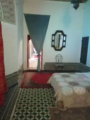 a bedroom with a bed and a mirror and a window at Suite in a 19 century palace in the heart of Medina in Fès