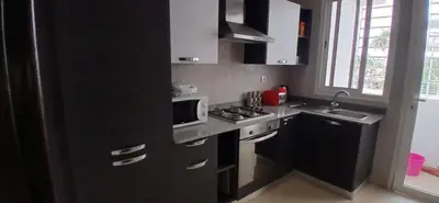 a black kitchen with a microwave and a stove at Prestige house in Oulad Akkou