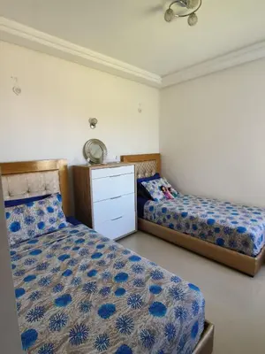 a bedroom with two beds and a dresser at Le bleu d Olablanca in Zaouia Sidi Rahkal