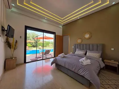 a bedroom with a bed and a view of a pool at Villa Nomade Residence 3 chambres avec piscine in Oulad Snaguia