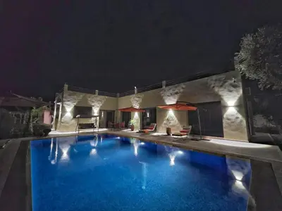 a large blue swimming pool at night at Villa Nomade Residence 3 chambres avec piscine in Oulad Snaguia