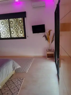 a bedroom with a bed and a tv on a wall at Villa Nomade Residence 3 chambres avec piscine in Oulad Snaguia