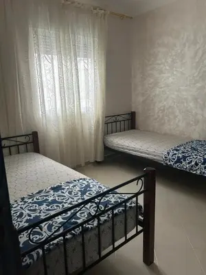 two twin beds in a room with a window at Social appartement at Martil in Oulad Akkou