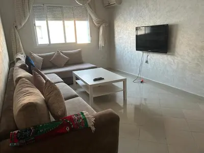 a living room with a couch and a tv at Social appartement at Martil in Oulad Akkou