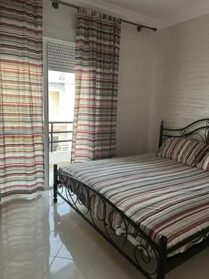 a bed in a room with curtains and a window at Social appartement at Martil in Oulad Akkou