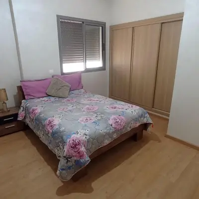 a bedroom with a bed with a floral comforter and a window at Vacation apartment in Oulad Akkou