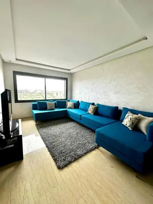 a living room with a blue couch and a television at Appartment central view on Hassan II in Oulad Akkou