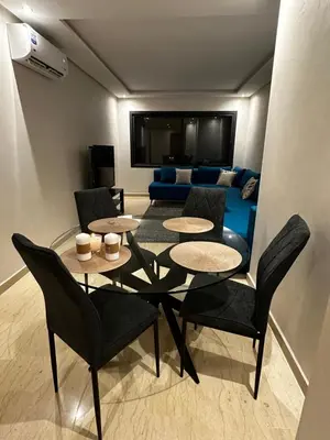a living room with a table and chairs and a couch at Appartment central view on Hassan II in Oulad Akkou