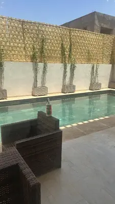 a swimming pool with potted plants on a wall at Villa À Kenza marrakech in Oulad Akkou