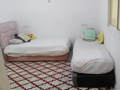 two twin beds in a room with a carpet at appartement meuble in Oulad Akkou