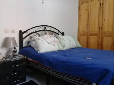 a bedroom with a bed with blue sheets and pillows at appartement meuble in Oulad Akkou
