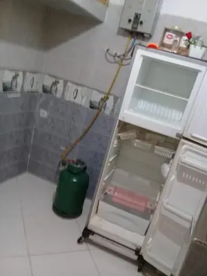 a kitchen with an open refrigerator with a green pot at appartement meuble in Oulad Akkou